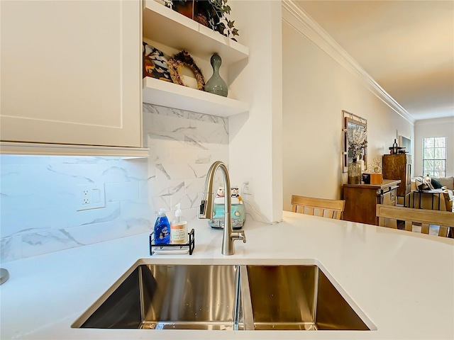 kitchen featuring tasteful backsplash, ornamental molding, and sink