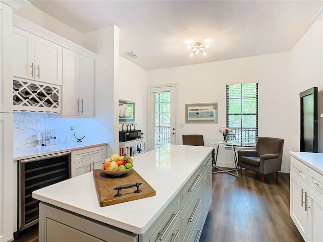 kitchen featuring decorative backsplash, a kitchen island, white cabinetry, dark hardwood / wood-style floors, and wine cooler