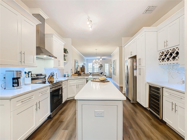 kitchen featuring wall chimney range hood, dark hardwood / wood-style floors, kitchen peninsula, stainless steel appliances, and beverage cooler