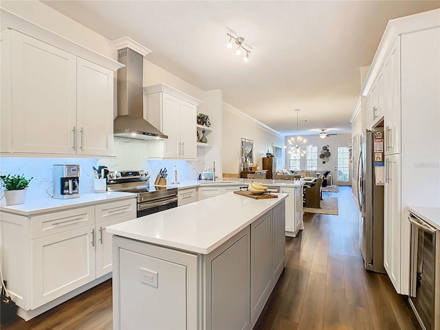 kitchen featuring wall chimney range hood, dark hardwood / wood-style floors, a kitchen island, kitchen peninsula, and stainless steel appliances