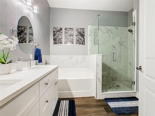 bathroom with wood-type flooring, vanity, and shower with separate bathtub