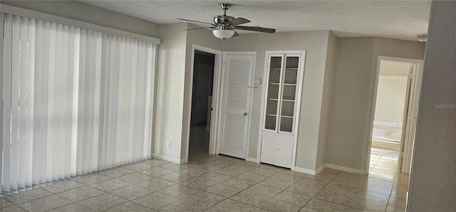 tiled empty room with ceiling fan and a textured ceiling