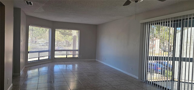 tiled empty room featuring ceiling fan, a healthy amount of sunlight, and a textured ceiling