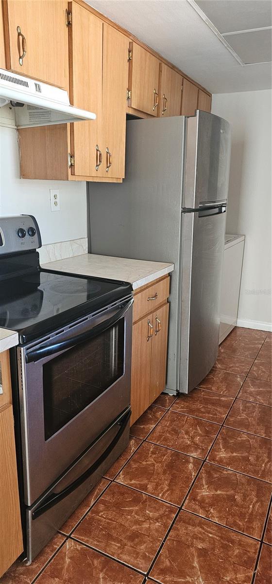 kitchen with stainless steel appliances and dark tile patterned floors