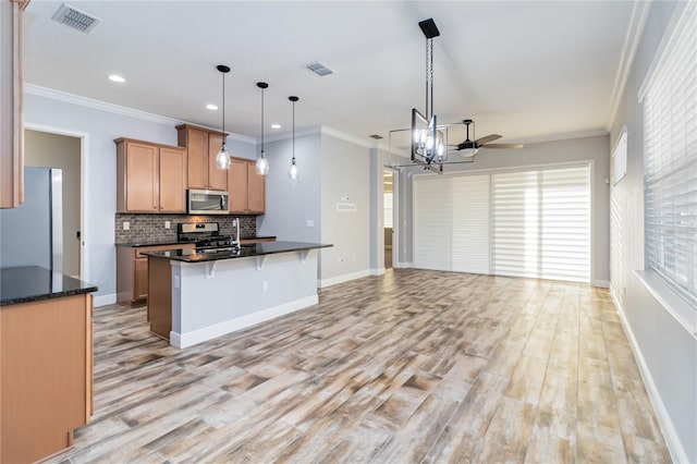 kitchen with light wood-type flooring, stainless steel appliances, hanging light fixtures, and crown molding