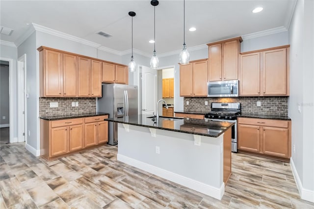 kitchen with dark stone counters, stainless steel appliances, crown molding, pendant lighting, and a center island with sink