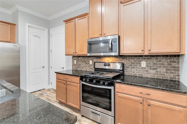 kitchen featuring dark stone countertops, stainless steel appliances, and ornamental molding