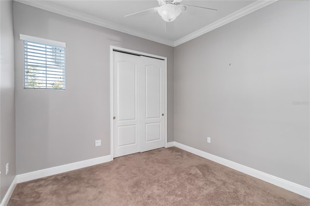 unfurnished bedroom featuring light carpet, a closet, ceiling fan, and crown molding