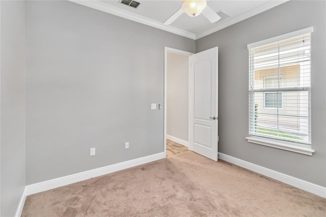 carpeted empty room featuring a wealth of natural light, ceiling fan, and ornamental molding