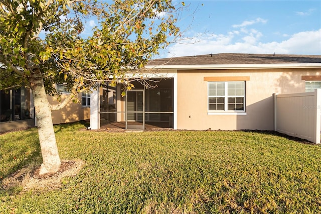 back of property with a lawn and a sunroom