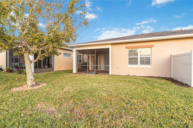 rear view of property featuring a lawn and a sunroom