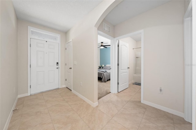 foyer entrance with ceiling fan and a textured ceiling