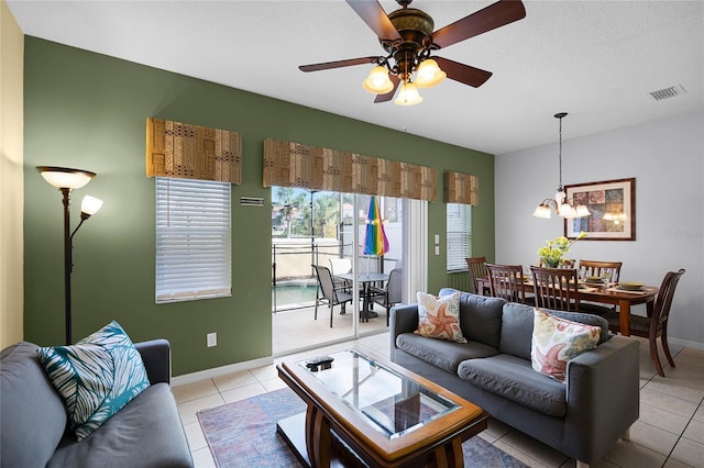 tiled living room featuring a textured ceiling and ceiling fan with notable chandelier