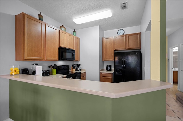 kitchen featuring kitchen peninsula, light tile patterned floors, black appliances, and a textured ceiling