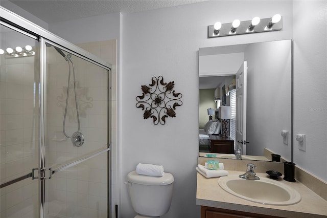 bathroom featuring a textured ceiling, vanity, toilet, and a shower with door