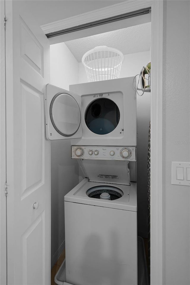 clothes washing area with stacked washing maching and dryer