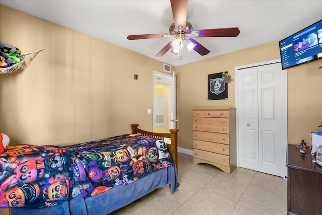 tiled bedroom featuring ceiling fan, a textured ceiling, and a closet