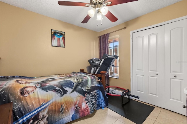 bedroom featuring ceiling fan, a closet, light tile patterned floors, and a textured ceiling