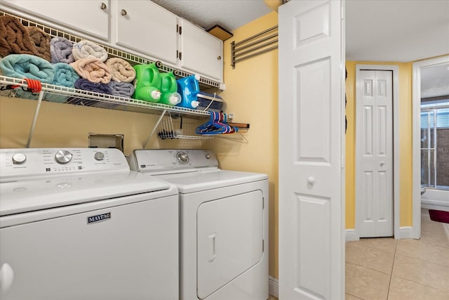 washroom with washer and clothes dryer, cabinets, light tile patterned floors, and a textured ceiling