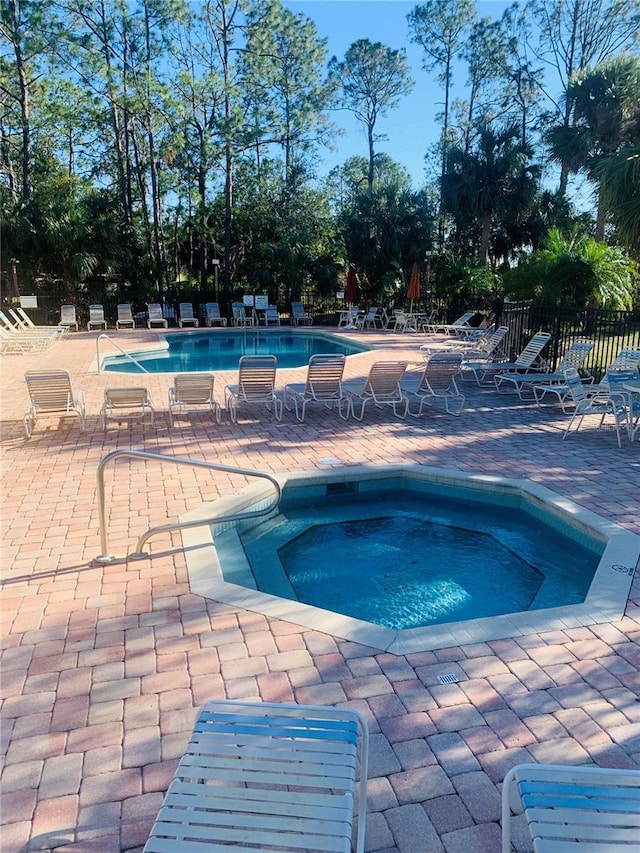 view of swimming pool with a hot tub and a patio area