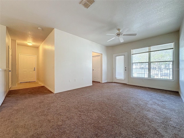 spare room featuring dark colored carpet, a textured ceiling, and ceiling fan