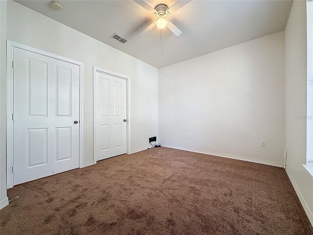 unfurnished bedroom with dark colored carpet and ceiling fan