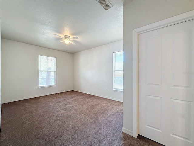 carpeted spare room featuring ceiling fan, a healthy amount of sunlight, and a textured ceiling