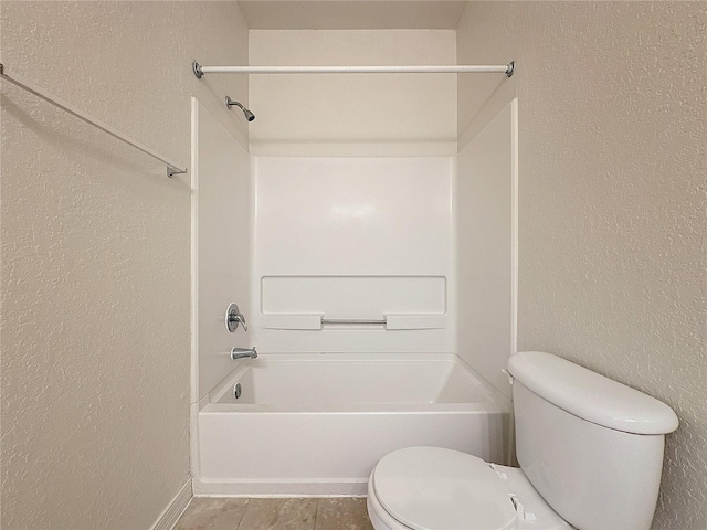 bathroom featuring tile patterned floors, toilet, and washtub / shower combination