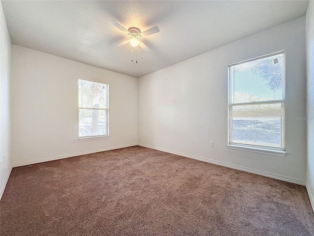 empty room with dark colored carpet and ceiling fan