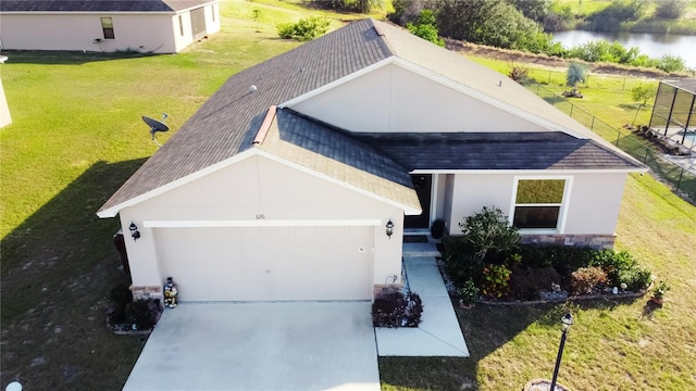 view of front of property with a garage, a water view, and a front yard