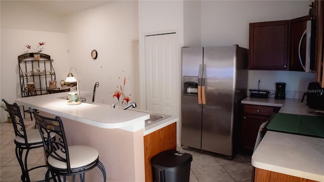 kitchen with sink, stainless steel appliances, a breakfast bar, light tile patterned flooring, and a center island with sink