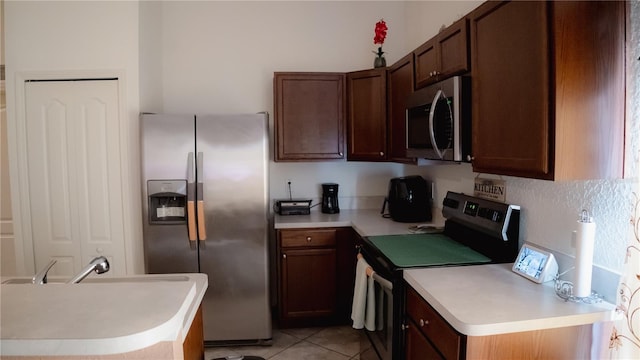 kitchen with light tile patterned floors, dark brown cabinetry, and stainless steel appliances