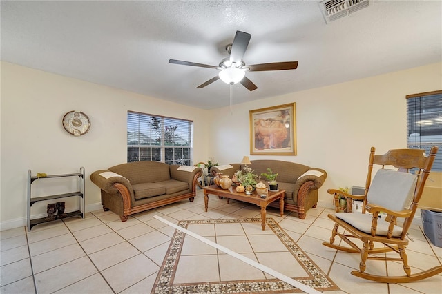 living room featuring light tile patterned flooring, ceiling fan, and a textured ceiling