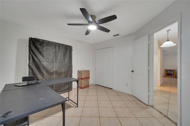 tiled home office featuring ceiling fan and a textured ceiling