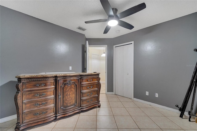 tiled bedroom featuring ceiling fan, a closet, and a textured ceiling