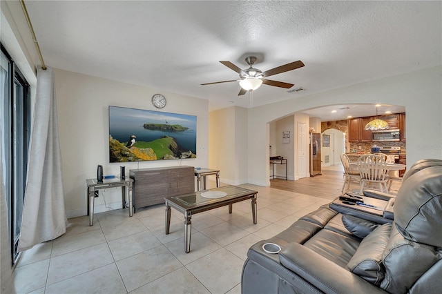 living room with light tile patterned floors, a textured ceiling, and ceiling fan