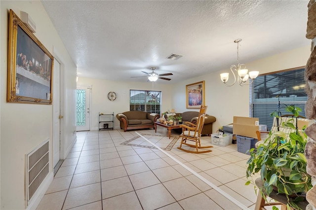 tiled living room featuring ceiling fan with notable chandelier and a textured ceiling