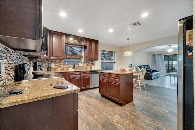 kitchen with hanging light fixtures, stainless steel appliances, a kitchen island, decorative backsplash, and light wood-type flooring