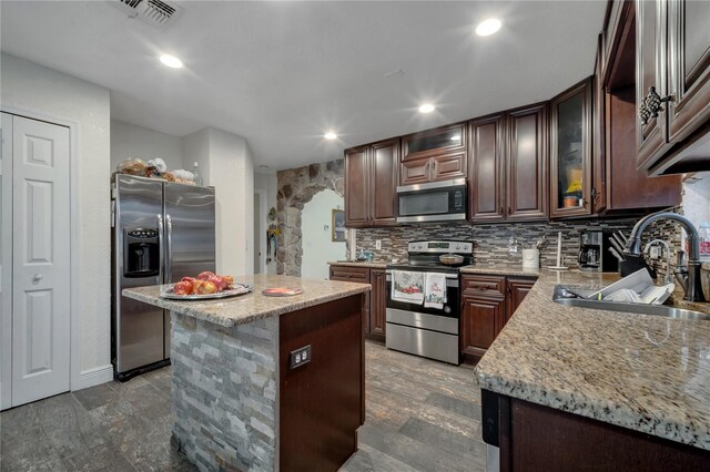 kitchen with dark brown cabinetry, sink, a kitchen island, and appliances with stainless steel finishes