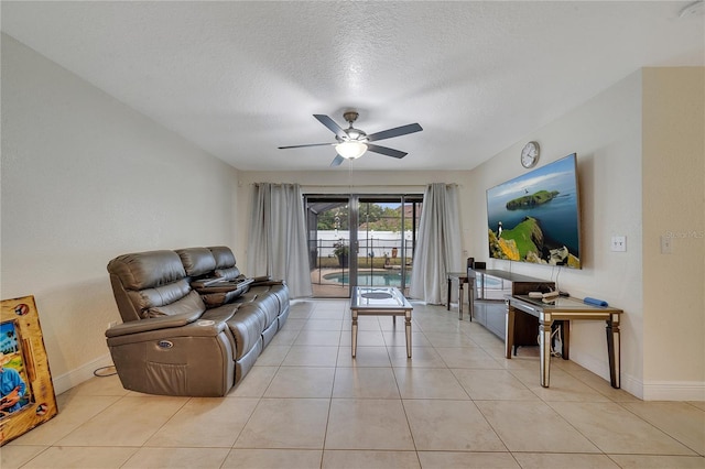 living room with ceiling fan, light tile patterned flooring, and a textured ceiling