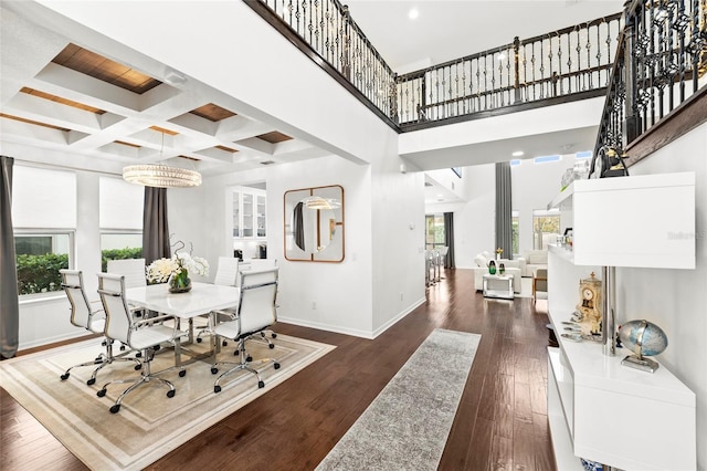 dining space with beam ceiling, coffered ceiling, dark hardwood / wood-style flooring, a towering ceiling, and a chandelier