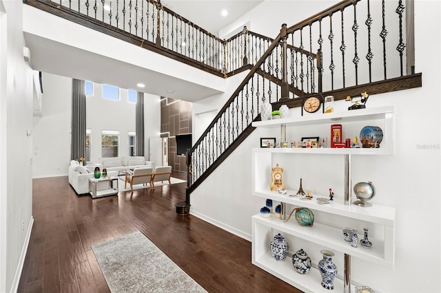 stairs with hardwood / wood-style floors and a towering ceiling