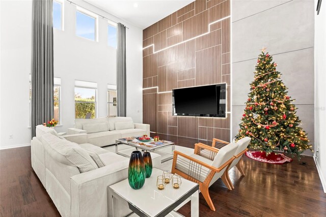 living room with a towering ceiling, dark hardwood / wood-style floors, and a healthy amount of sunlight