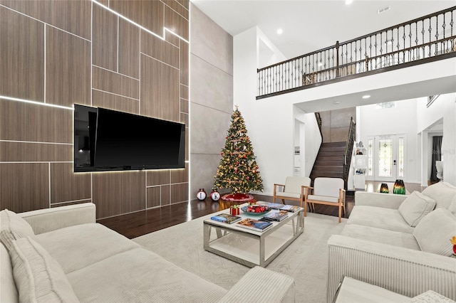 living room featuring french doors, a towering ceiling, and light wood-type flooring