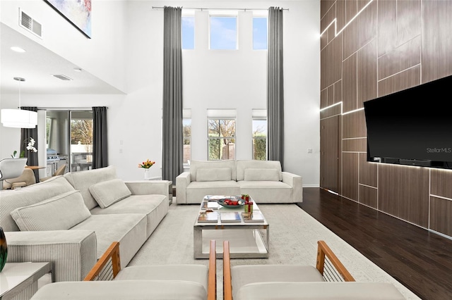 living room featuring a healthy amount of sunlight, a high ceiling, and hardwood / wood-style flooring