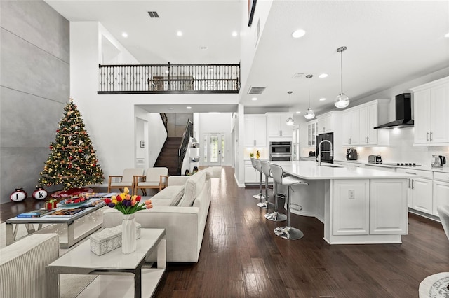 living room featuring dark hardwood / wood-style floors, sink, and a high ceiling