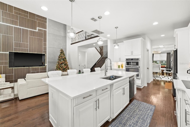 kitchen featuring dark hardwood / wood-style flooring, sink, decorative light fixtures, a center island with sink, and white cabinetry