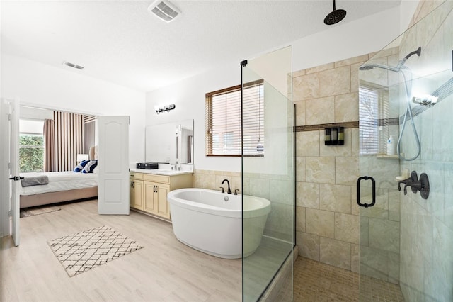 bathroom with a textured ceiling, vanity, independent shower and bath, tile walls, and hardwood / wood-style flooring