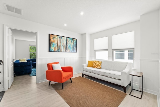 living room with a textured ceiling, light wood-type flooring, and cooling unit