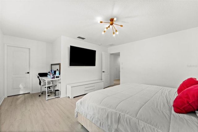 bedroom with light hardwood / wood-style floors and a notable chandelier